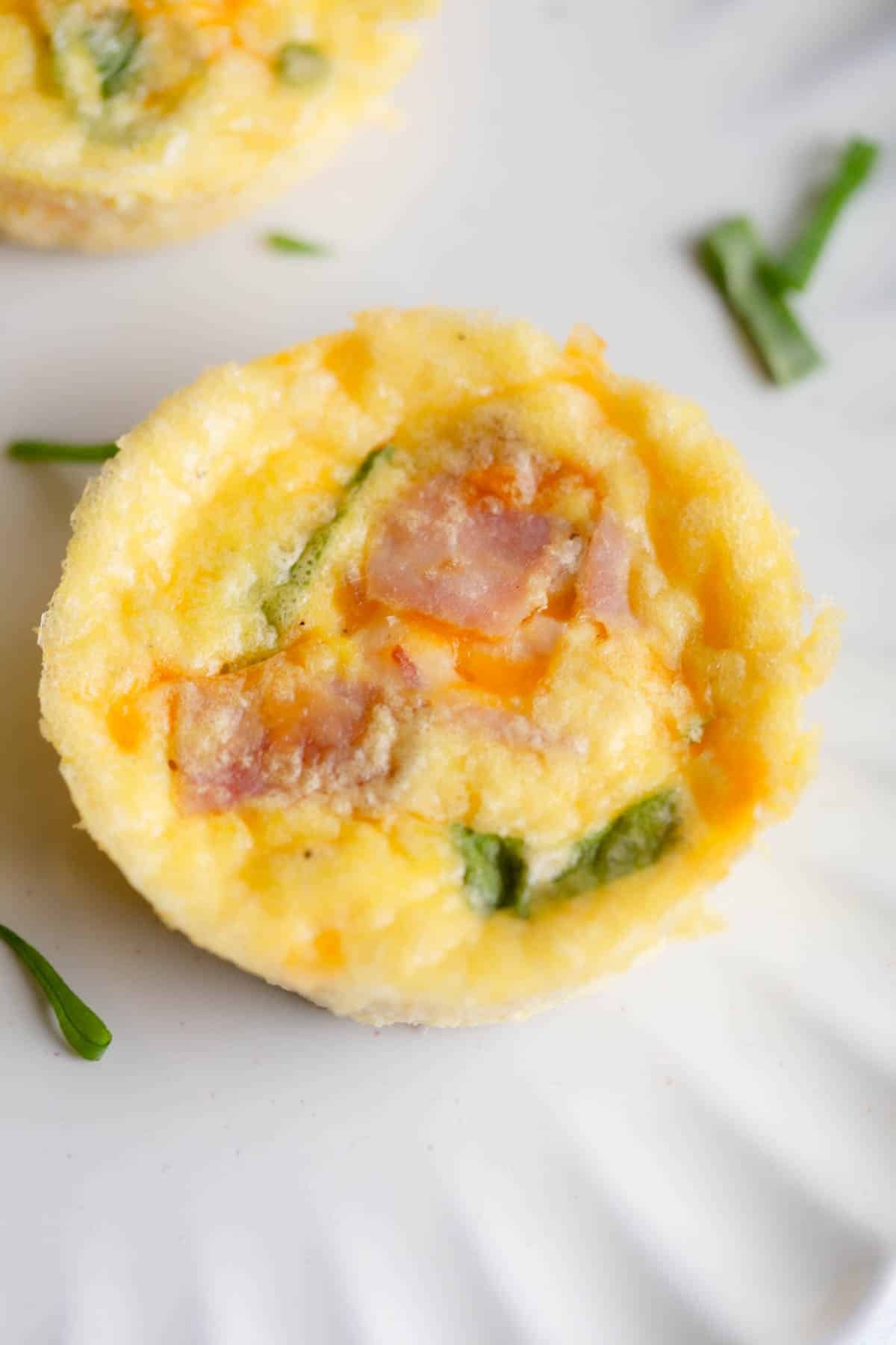 Cottage Cheese Egg Bite on a white plate with diced green onions scattered around. 