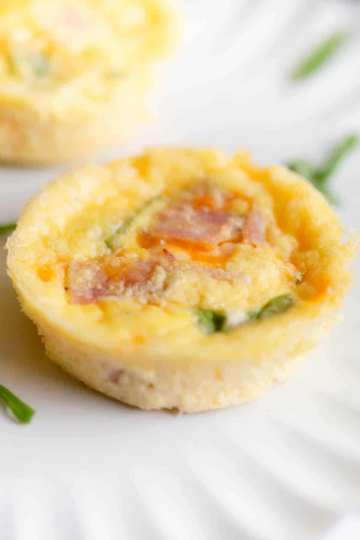 Cottage Cheese Egg Bites on a white plate with diced green onions scattered around it. 