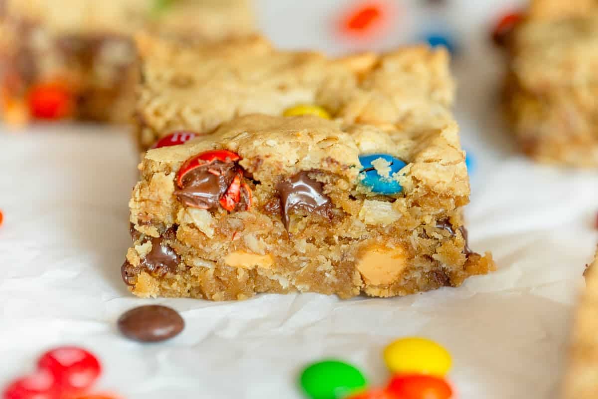 Monster Cookie Bar on a piece of parchment paper with M&M's scattered around them. 
