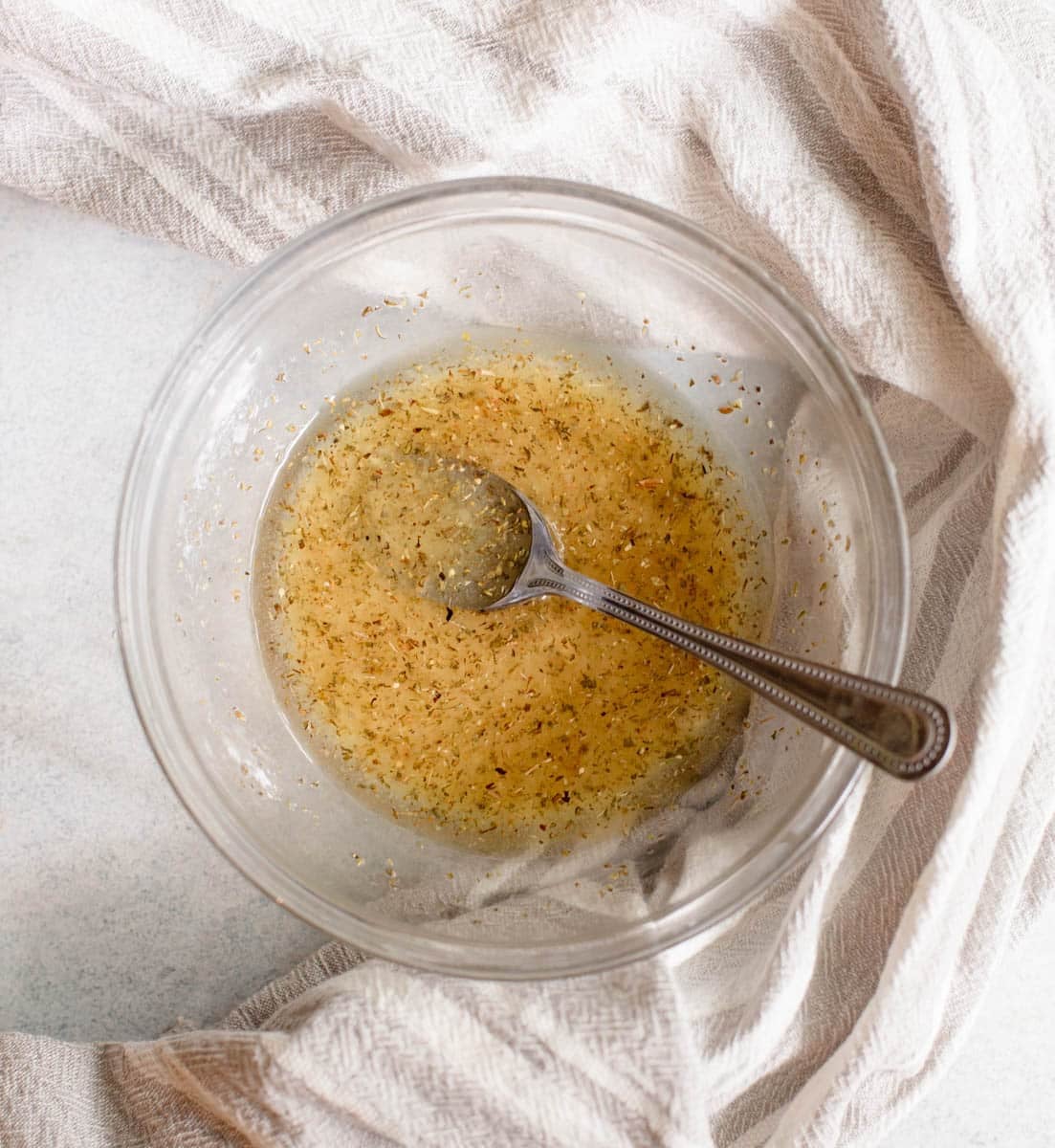 Lemon Vinaigrette dressing in a glass bowl with a spoon in it.