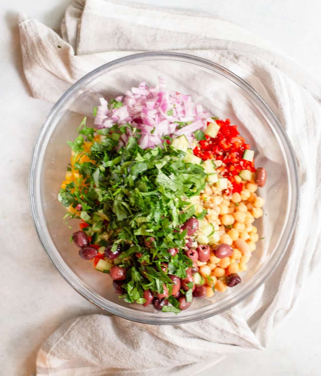 Vegetables beans and herbs in a glass bowl.