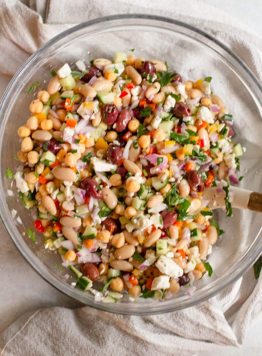 Greek Dense Bean Salad ingredients all mixed together in a glass bowl
