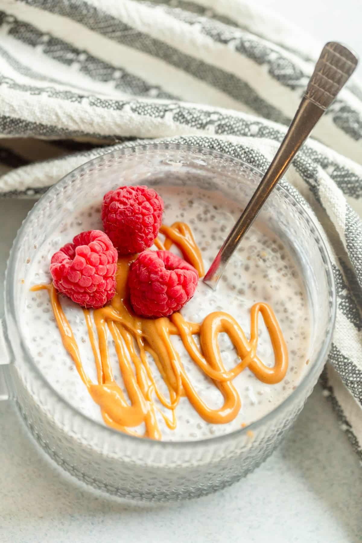 High Protein Chia Seed Pudding drizzled with peanut butter and topped with raspberries. 
