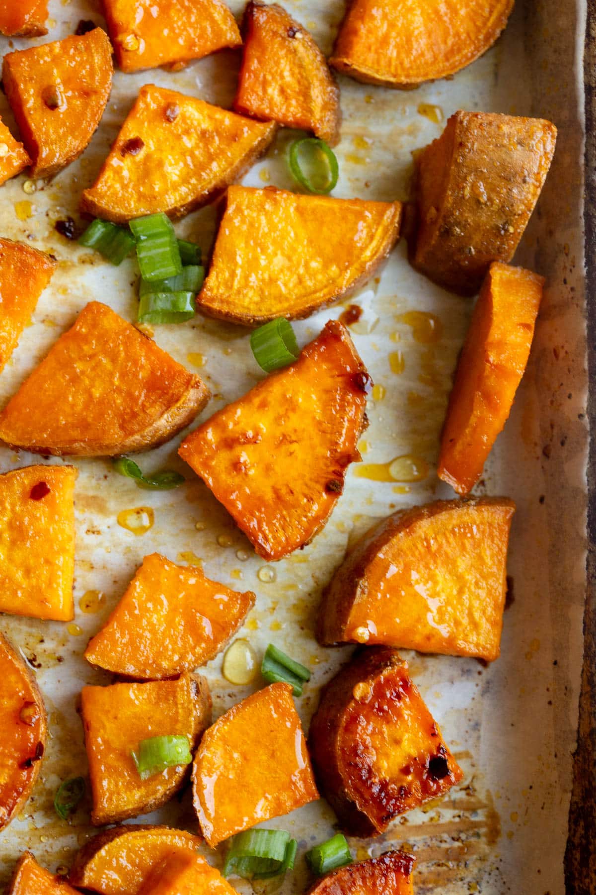 Hot Honey Sweet Potatoes on a baking sheet lined with parchment paper. 