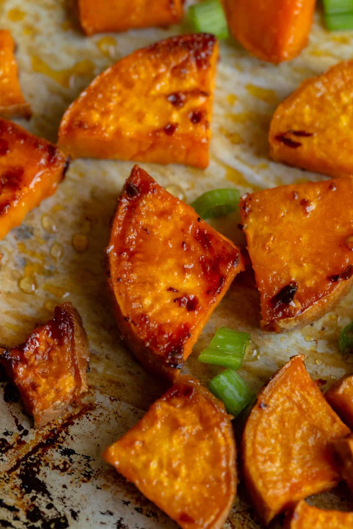 Hot Honey Sweet Potatoes on a baking sheet lined with parchment paper. 