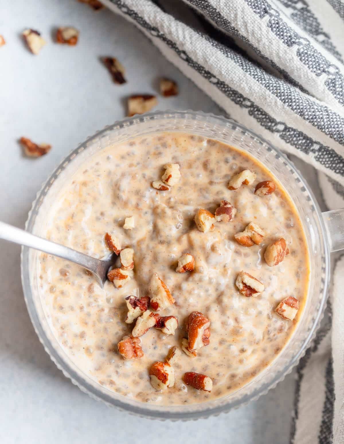 Pumpkin Chia Seed Pudding in a glass mug with a  handle, with pecans sprinkled on top.