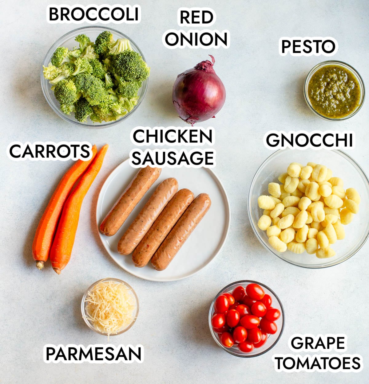 Ingredients in Sheet Pan Pesto Gnocchi and Sausage with a gray background.
