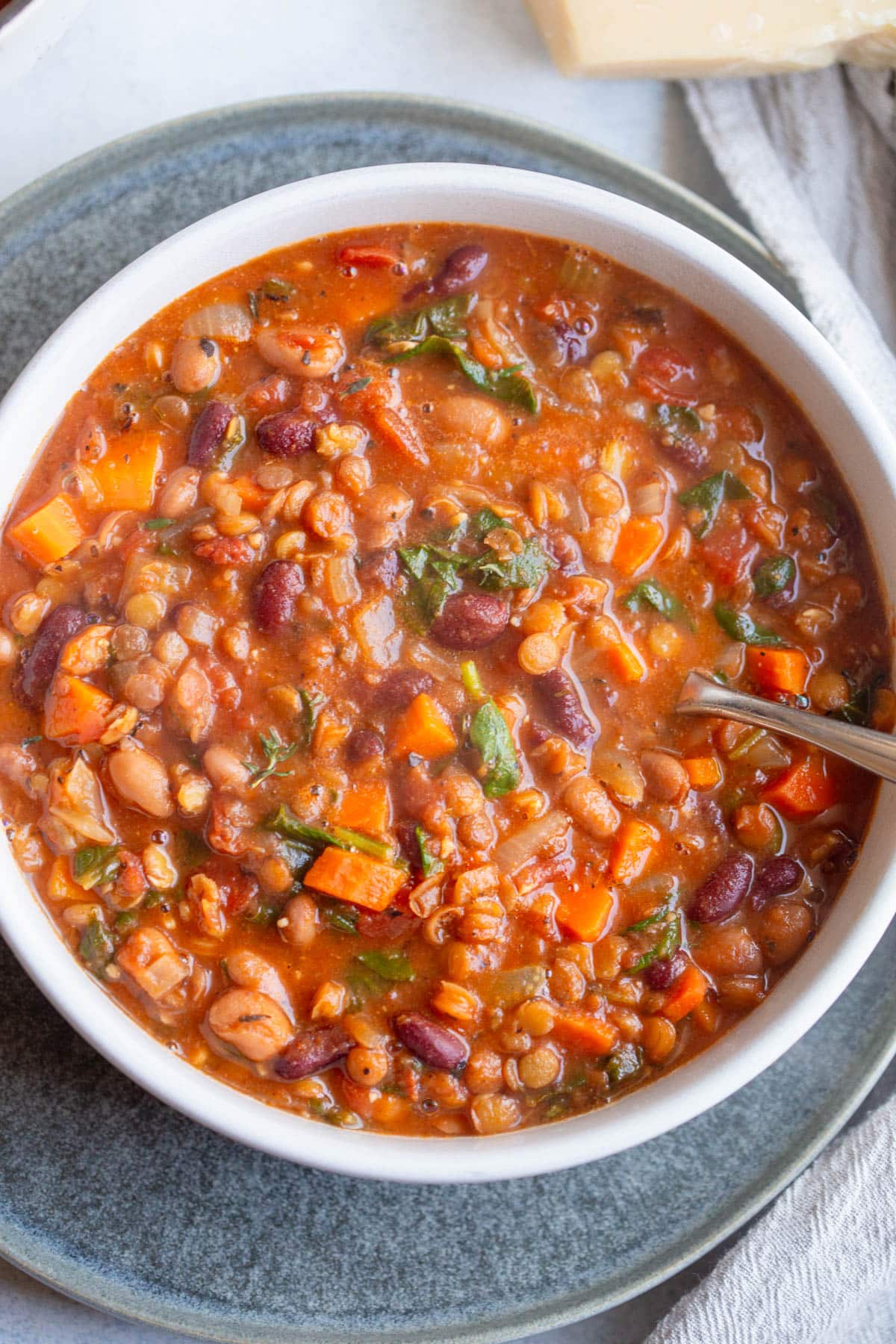 Lentil Bean Soup in a shallow cream colored bowl with a spoon resting in the soup. 