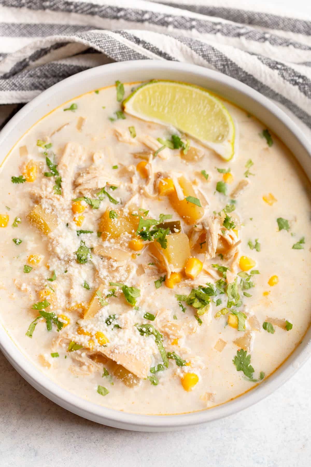 Slow Cooker Mexican Street Corn Soup in a cream colored bowl, topped with fresh chopped cilantro and cotija cheese. 