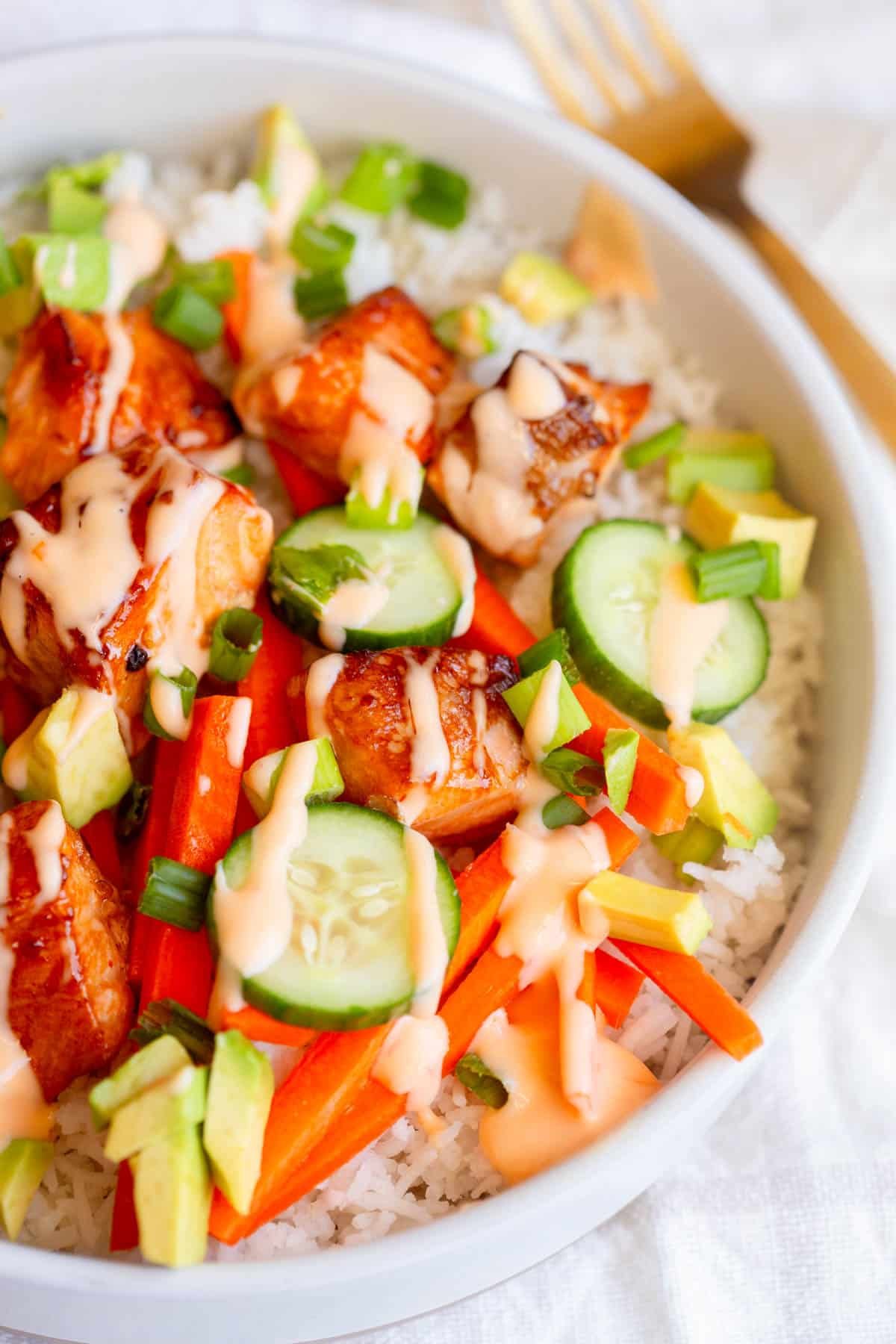 Air Fryer Salmon Bowls in a shallow bowl drizzled with sauce and garnished with green onions. 