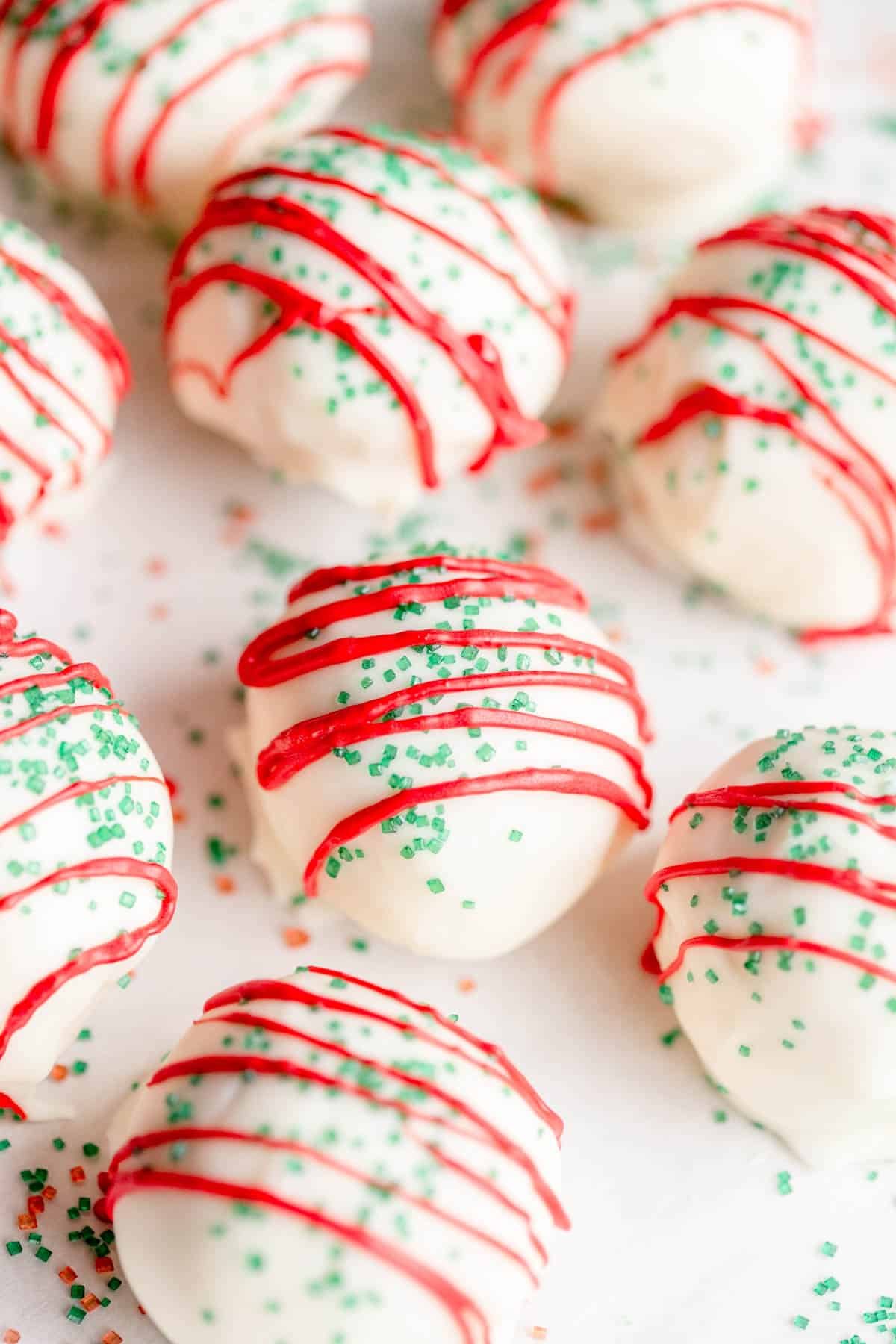 Little Debbie Christmas Tree Cake Pops on a baking sheet with a piece of parchment paper, with green and red sprinkles around them. 