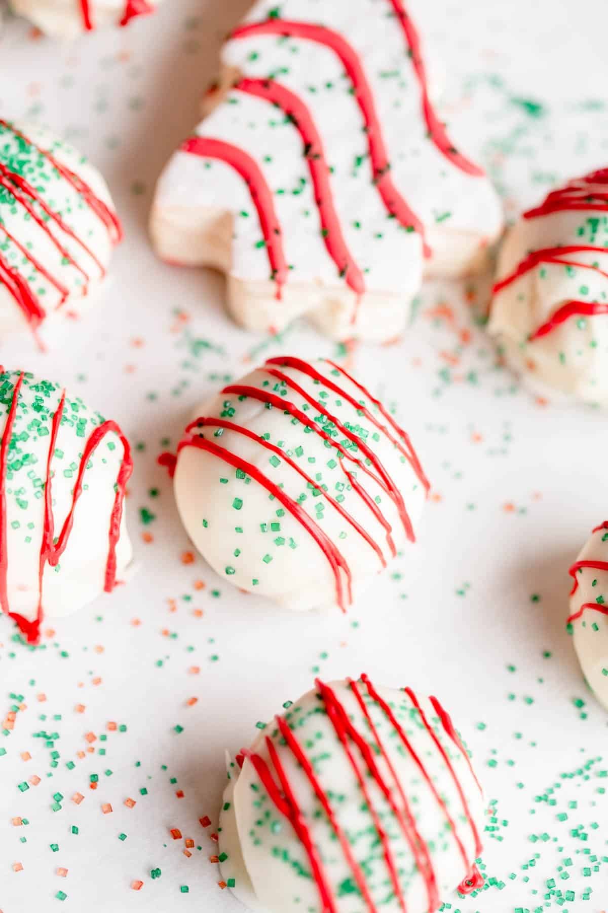 Little Debbie Christmas Tree Cake Pops on a parchment paper lined baking sheet with red and green sprinkles around them.