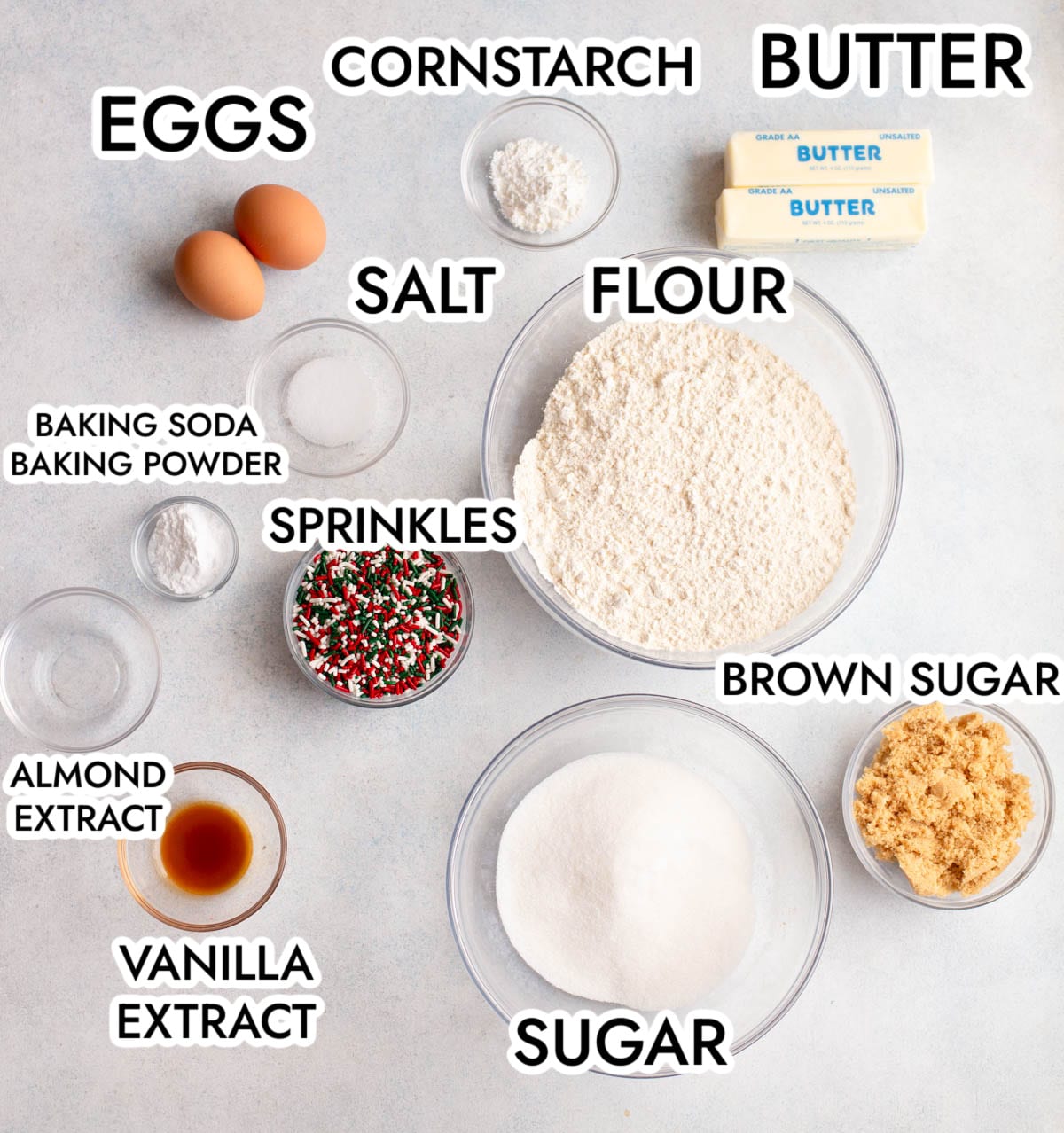 The ingredients in Christmas Sprinkle Sugar Cookies with a gray background, labeled with black text. 