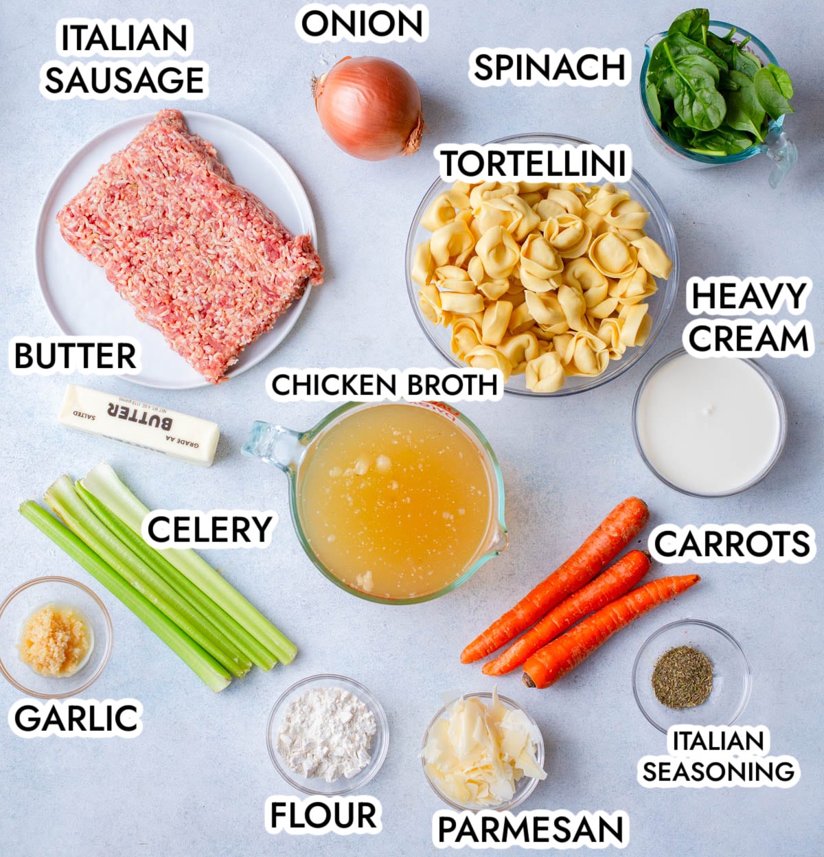 Ingredients in Creamy Sausage Tortellini Soup on a gray background labeled with black text.