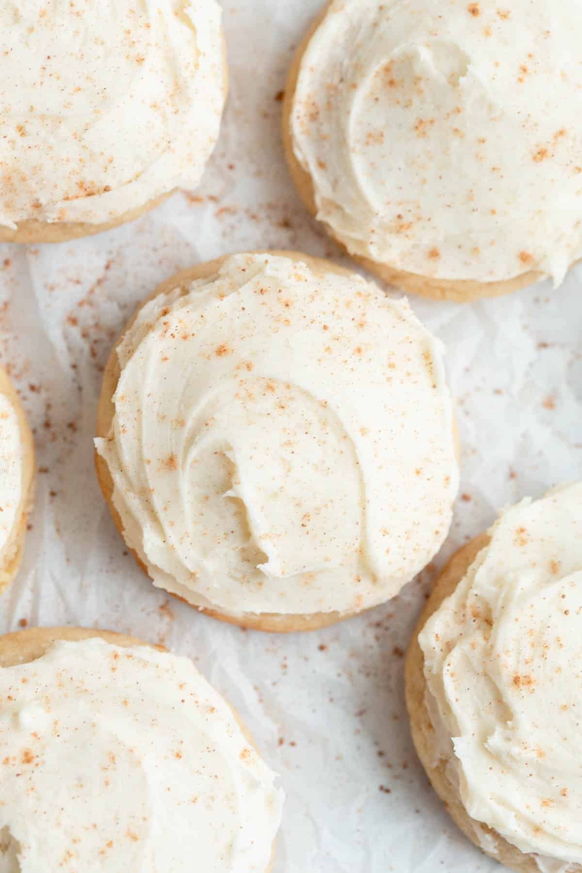 Eggnog Cookies with Eggnog Buttercream sprinkled with nutmeg on a piece of parchment paper. 
