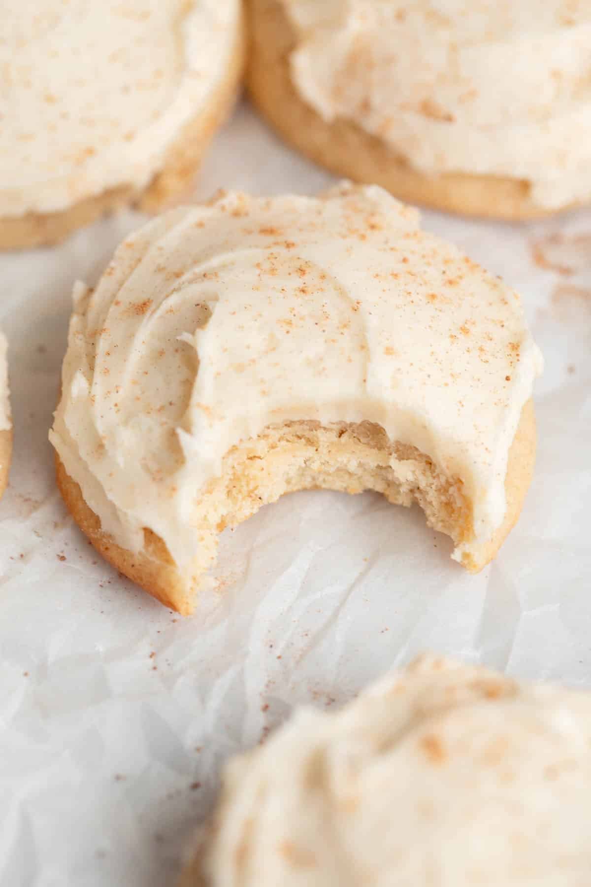 Eggnog Cookies with Eggnog Buttercream sprinkled with nutmeg on a piece of parchment paper. 