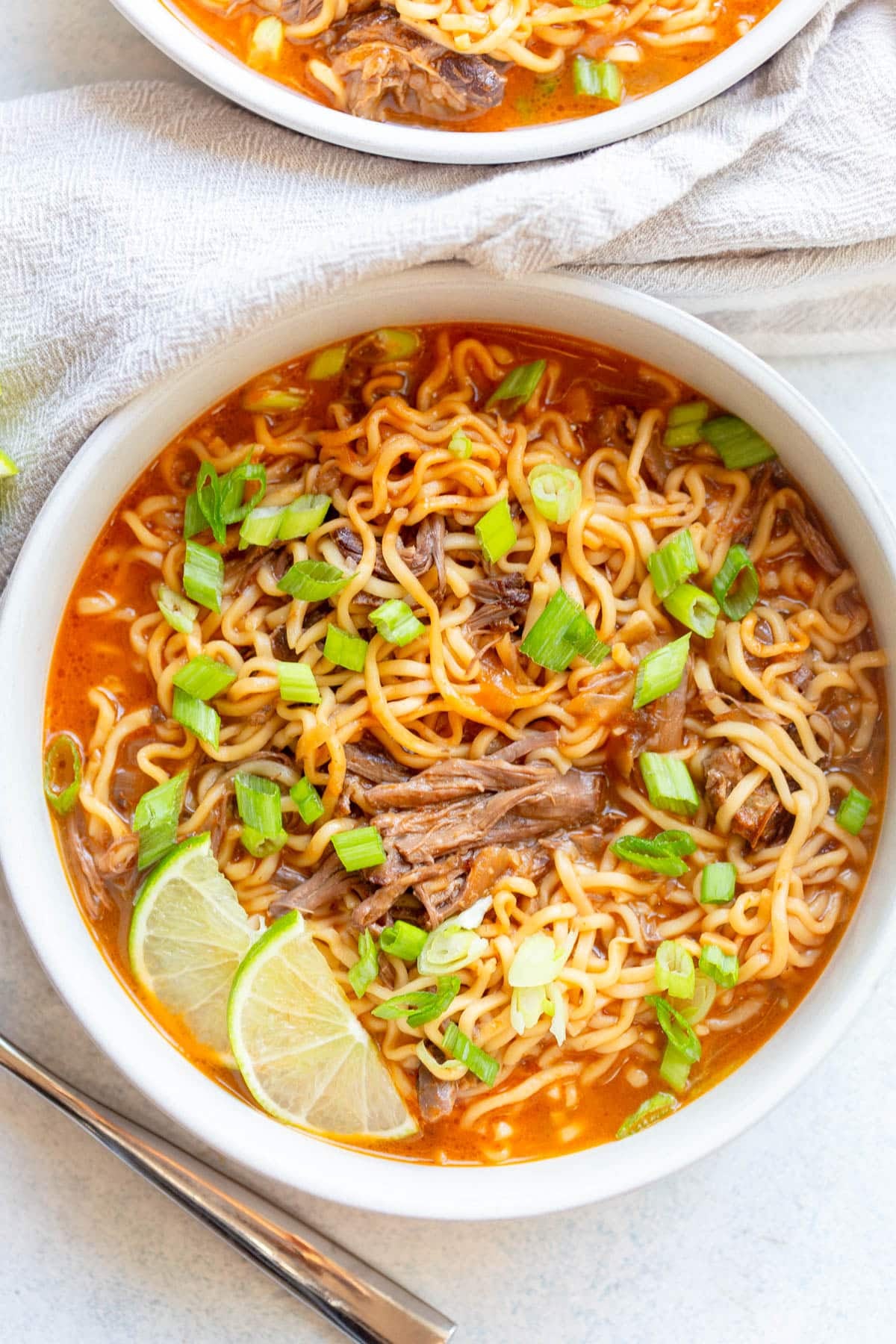 Short Rib Noodle Soup in a white bowl with diced green onions on top.