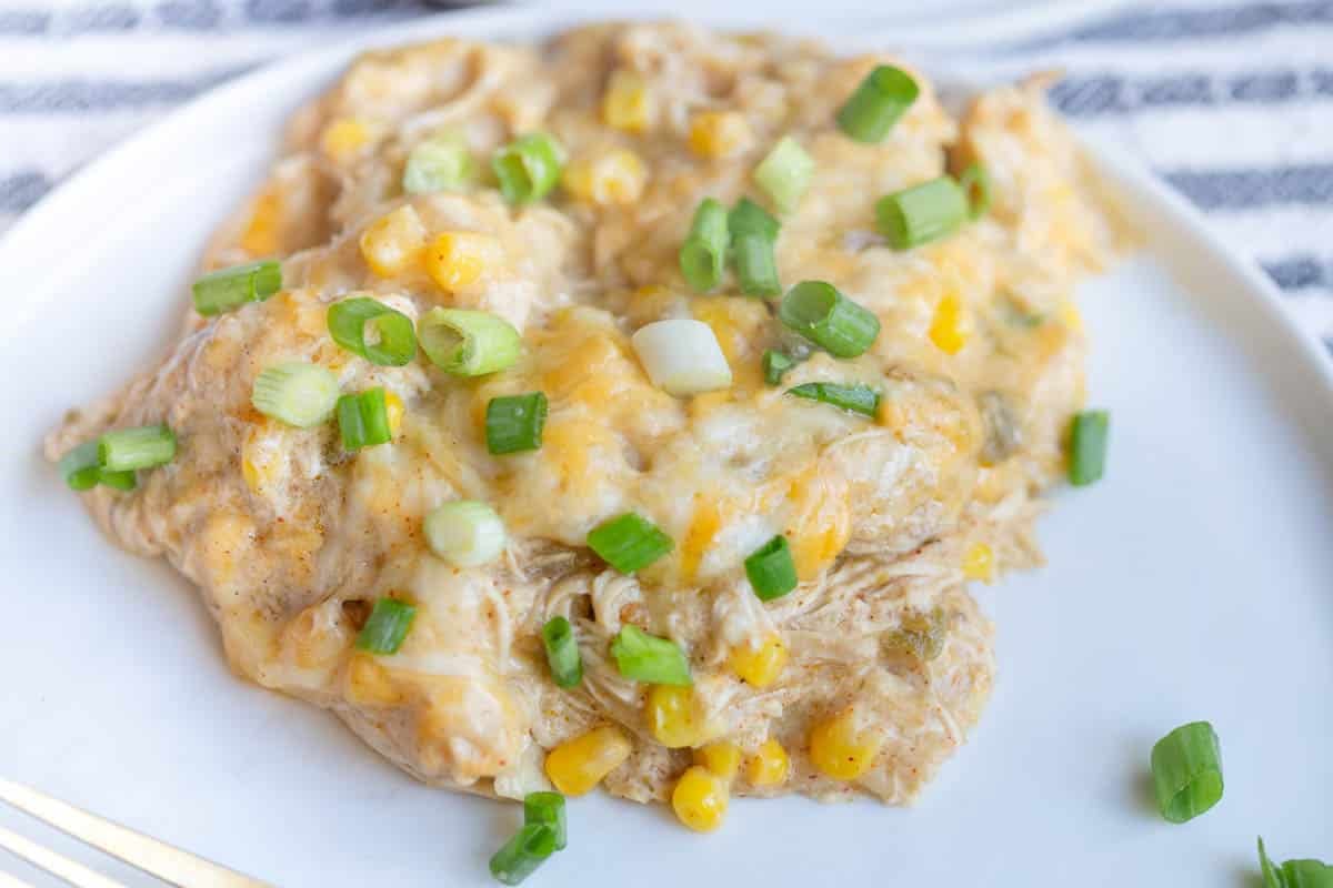 Slow Cooker Green Chicken Enchilada Casserole on a white plate with a striped napkin underneath.