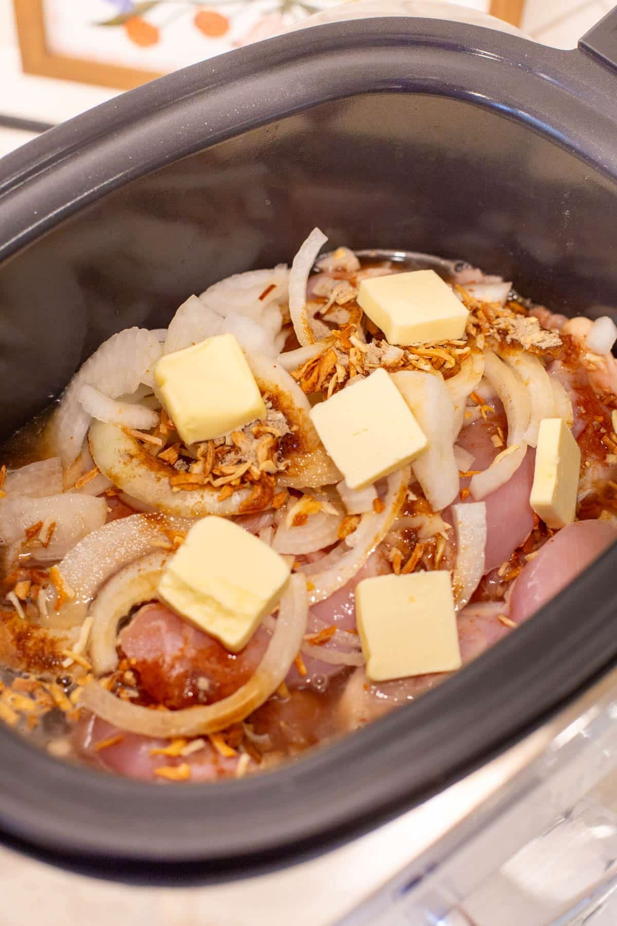 Slow Cooker French Onion Chicken Sliders process photo. Chicken, onions, and butter in a slow cooker.