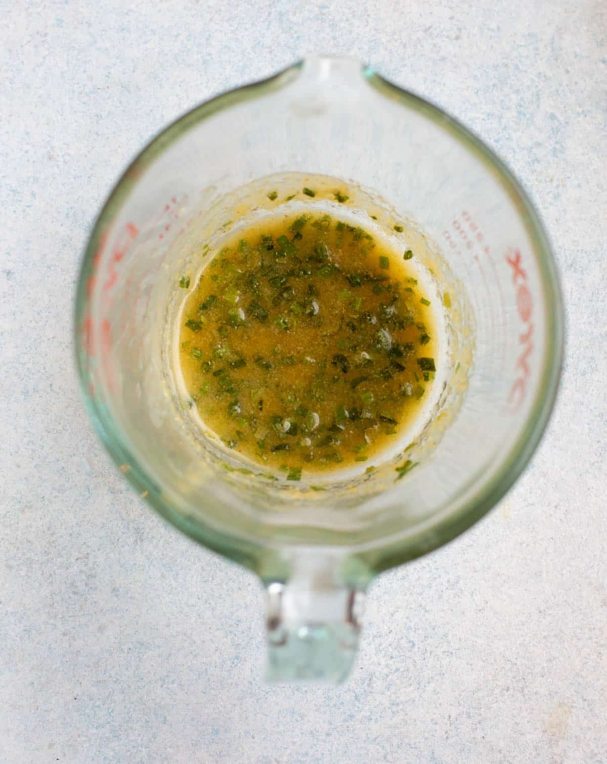 Melted butter, garlic powder, chives, and salt in a measuring cup.