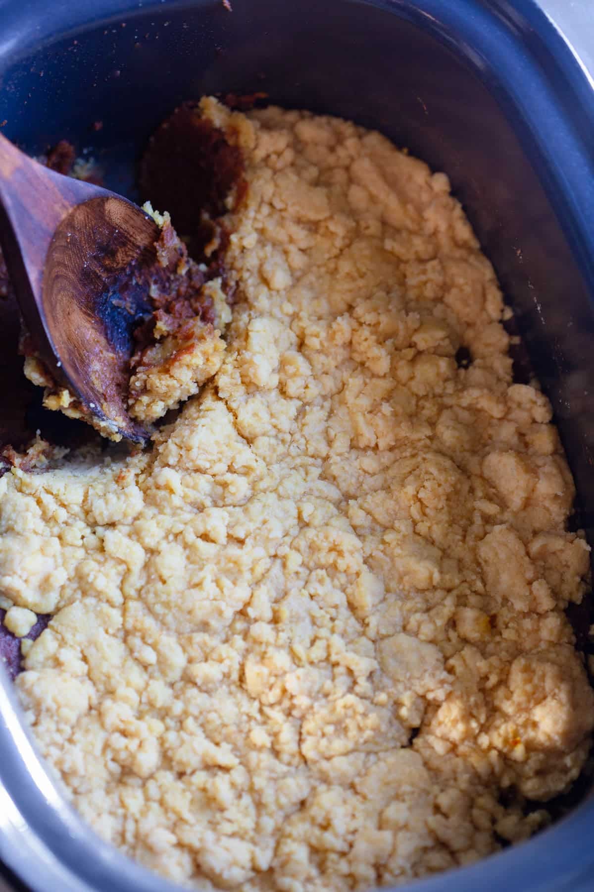 Slow Cooker Pumpkin Dump Cake in the slow cooker with a wooden spoon.